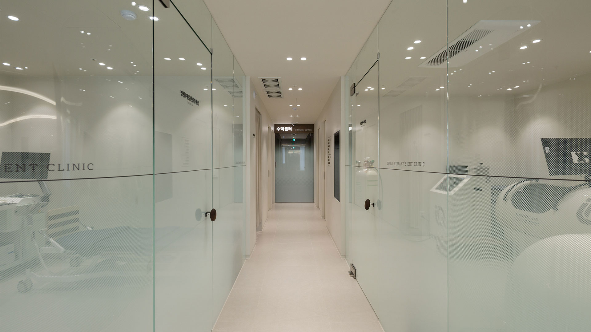 유리 벽으로 나뉜 방 사이 복도와 끝의 '수액센터 INFUSION CENTER' 안내판 사진