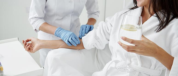 파란 장갑을 낀 의료진이 흰 가운 차림 여성의 팔을 잡고 있는 사진